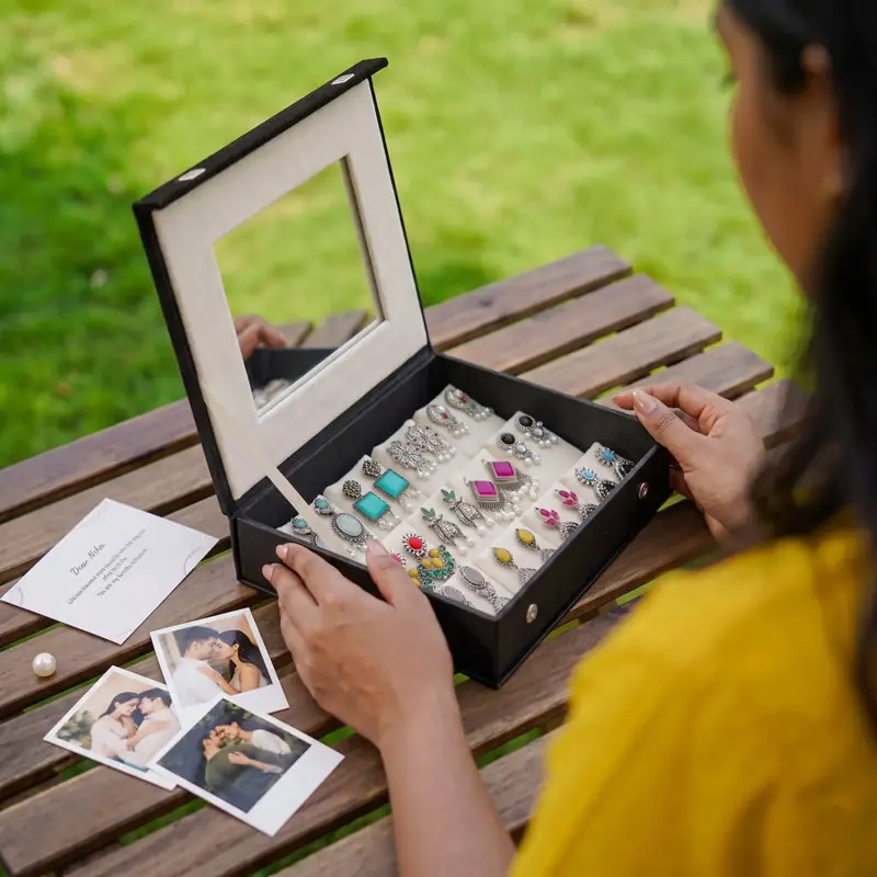 Colourful statement earrings in a mirror box on a garden table
